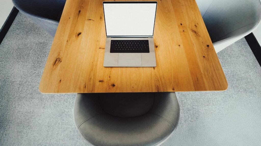 Aerial shot of a modern office desk setup with a laptop and chairs, ideal for corporate presentations.