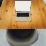 Aerial shot of a modern office desk setup with a laptop and chairs, ideal for corporate presentations.