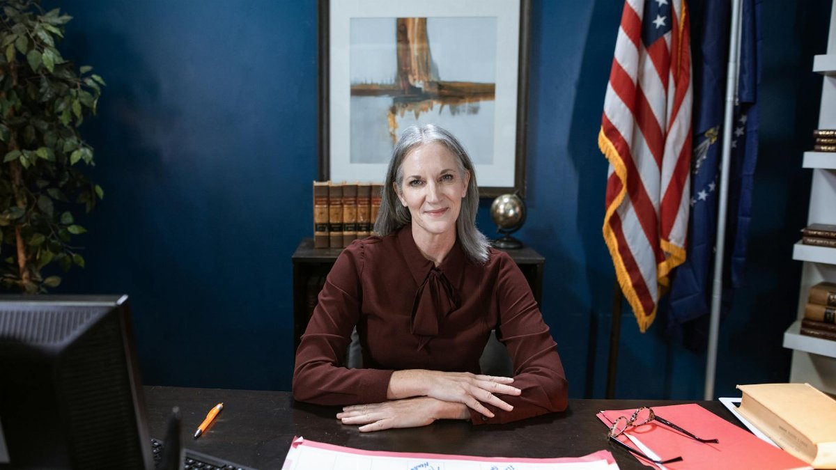 Professional woman in office with flags, showcasing leadership and confidence.