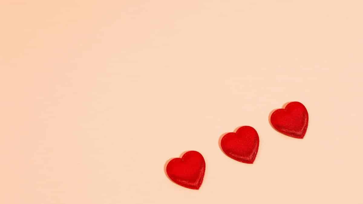 Three red heart shapes on pastel pink background with copy space.