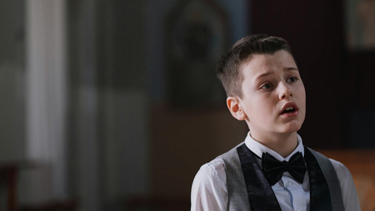 Portrait of a young choir boy singing with emotion in a church setting.