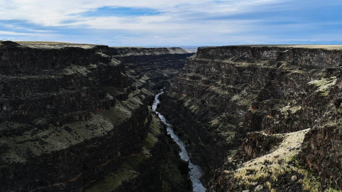 Breathtaking view of a deep canyon with a river cutting through, under a vibrant sky in Idaho.
