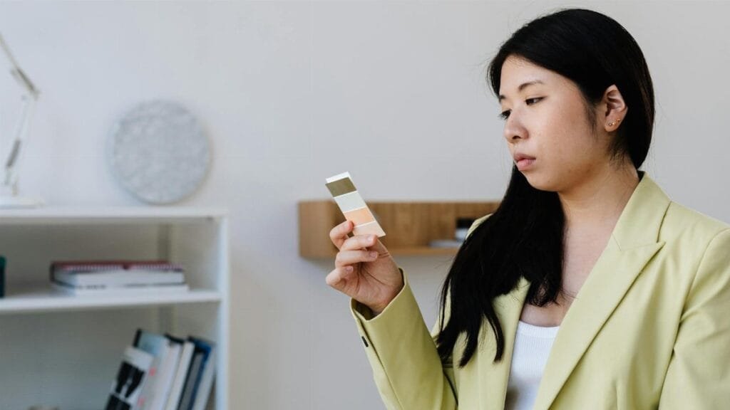 Woman in office attire holding color swatches, contemplating selection.