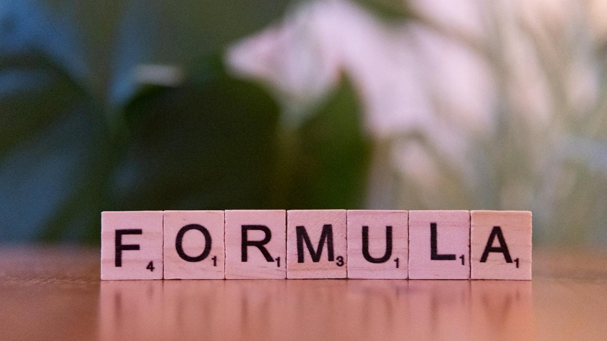 Close-up of Scrabble tiles spelling 'Formula' on a wooden surface with a blurred background.