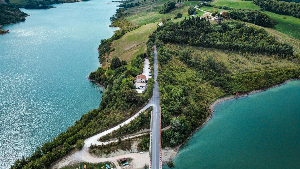 A spectacular aerial view of an island connected by a bridge over a serene lake, surrounded by lush landscapes.