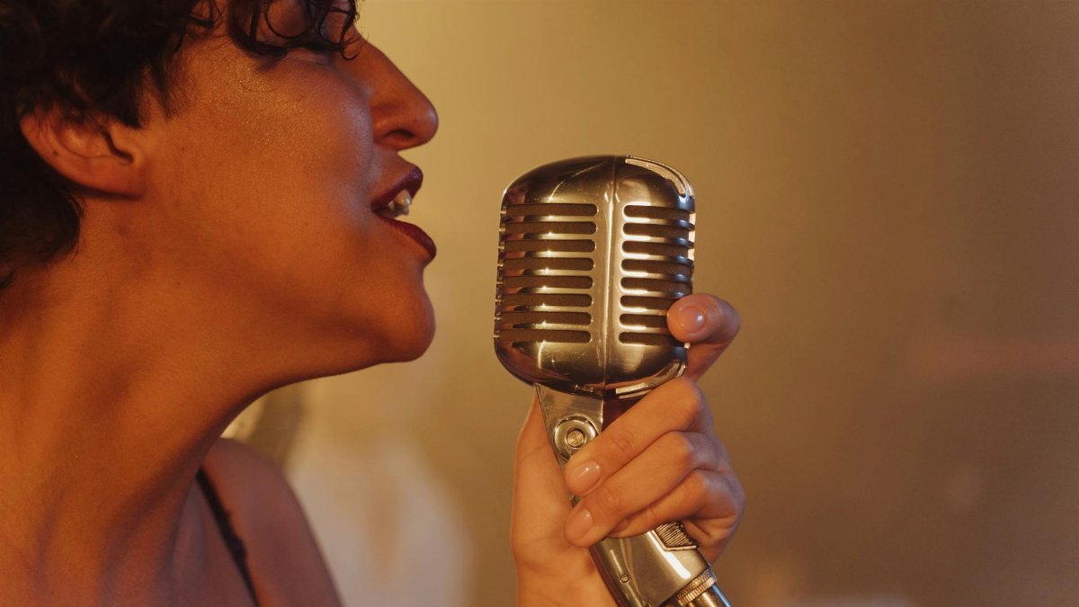 Close-up of a female jazz singer passionately performing with a vintage microphone.