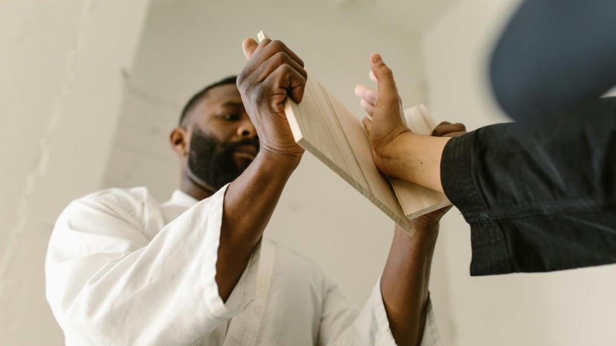 Martial artist breaking a board during training in dojo. Intense focus and skill.