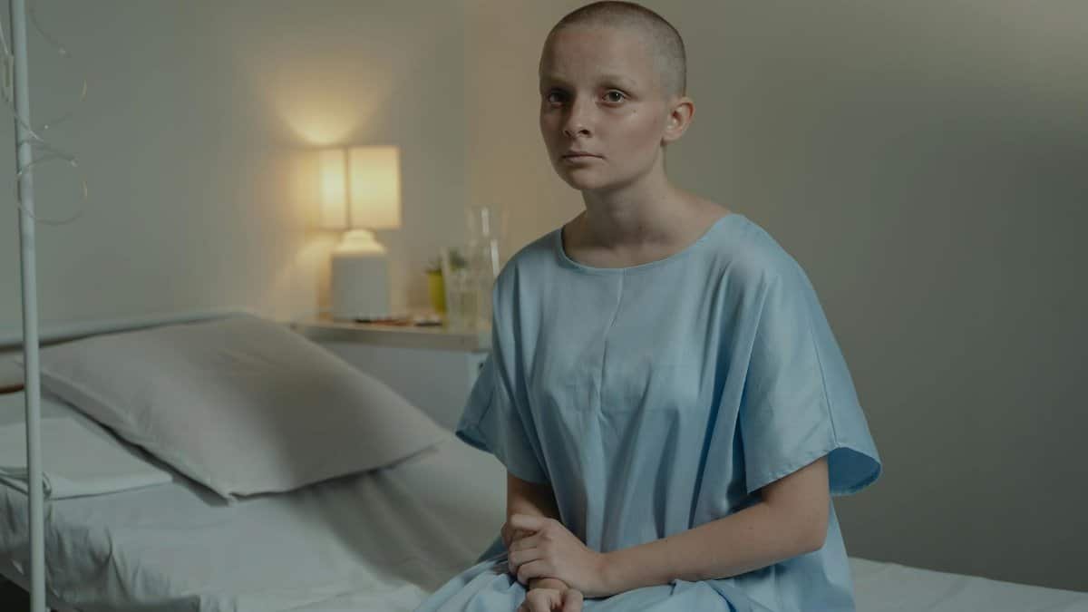 A young patient in a hospital room wearing a blue gown, conveying a calm mood.