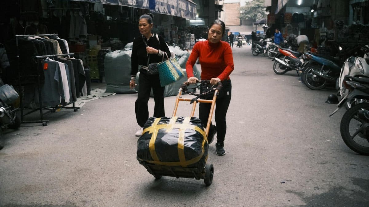 Two women navigate a busy market, emphasizing urban hustle and everyday life.