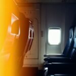 Interior view of empty airplane seats next to a window with warm lighting effect.