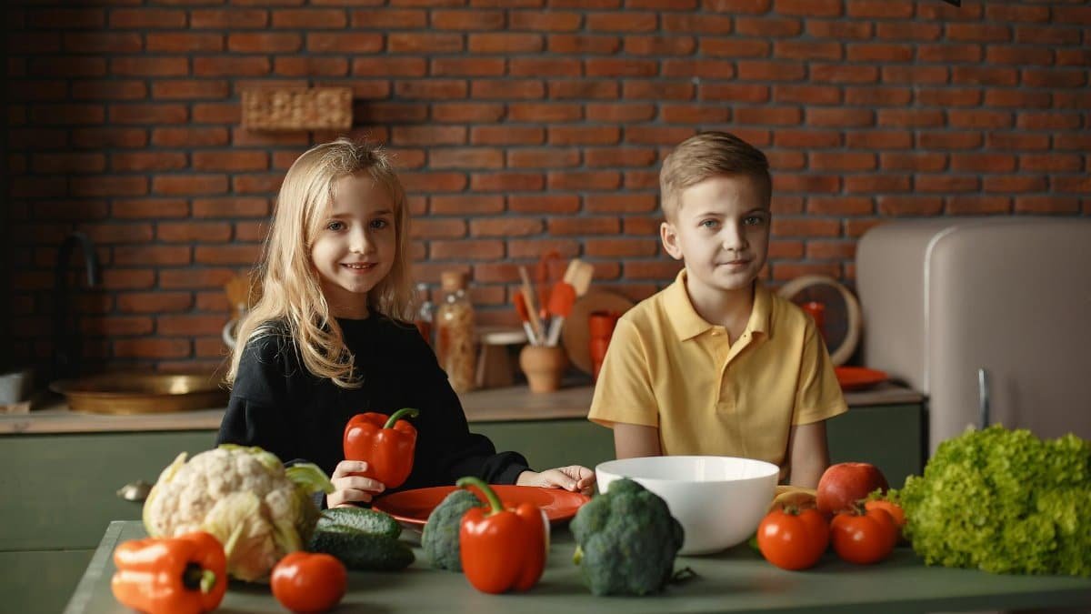 Two kids preparing fresh vegetable salad together in a cozy kitchen setting.