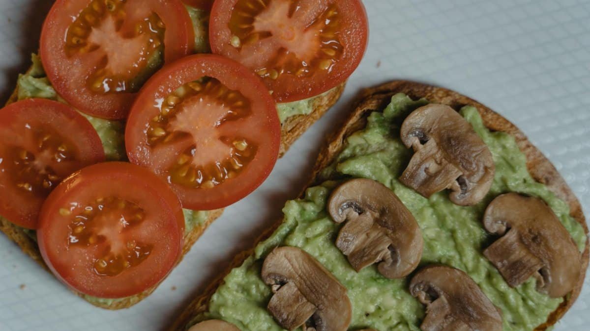 Close-up of avocado toasts topped with fresh tomatoes and mushrooms, a healthy vegan snack.