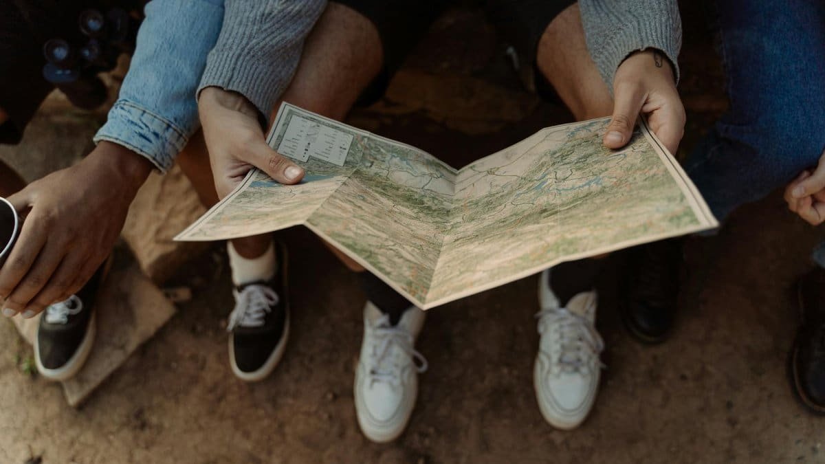 Close-up of a group exploring a map, planning a travel adventure while sitting outdoors.