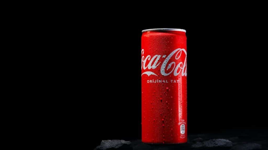 Close-up of a red Coca Cola can with water drops, shot in a studio with a black background.