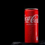 Close-up of a red Coca Cola can with water drops, shot in a studio with a black background.