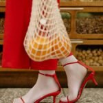 Stylish shopping scene with red heels and reusable net bag at grocery store.