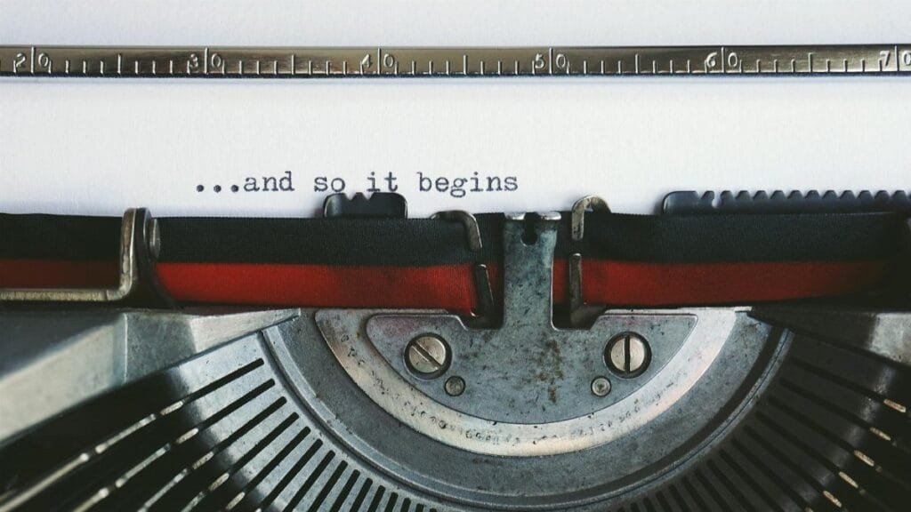 Close-up of a vintage typewriter with the quote '...and so it begins'.