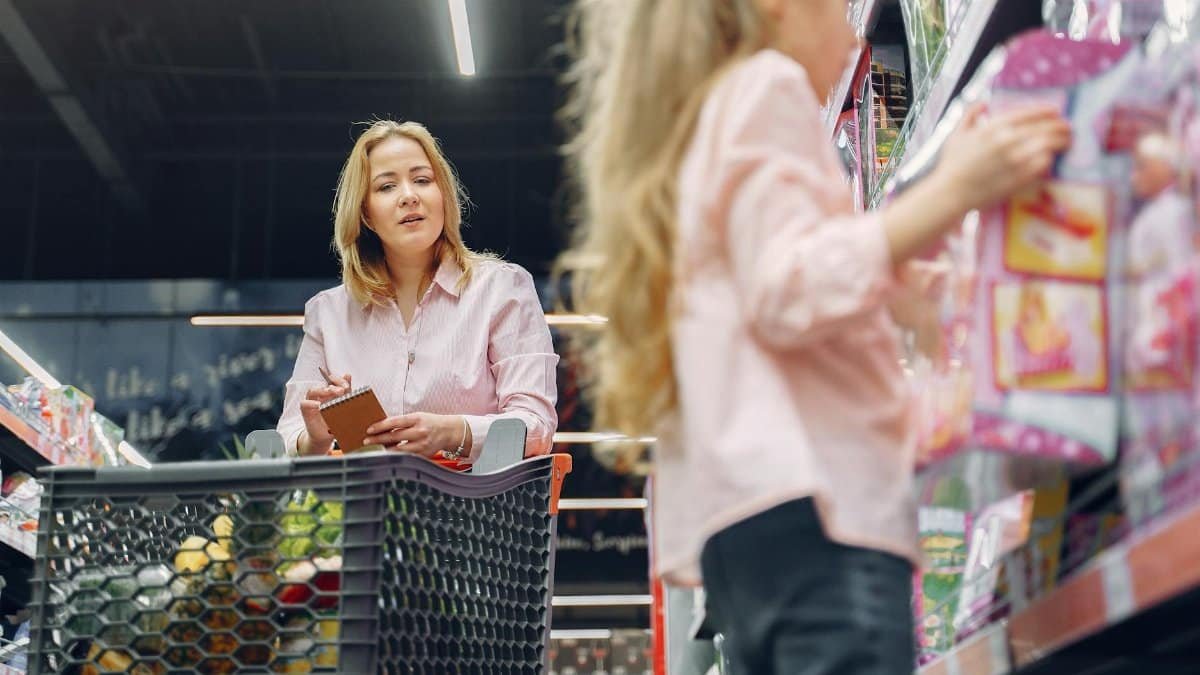 Mother and daughter shopping together in a supermarket, focused on selecting the right products.
