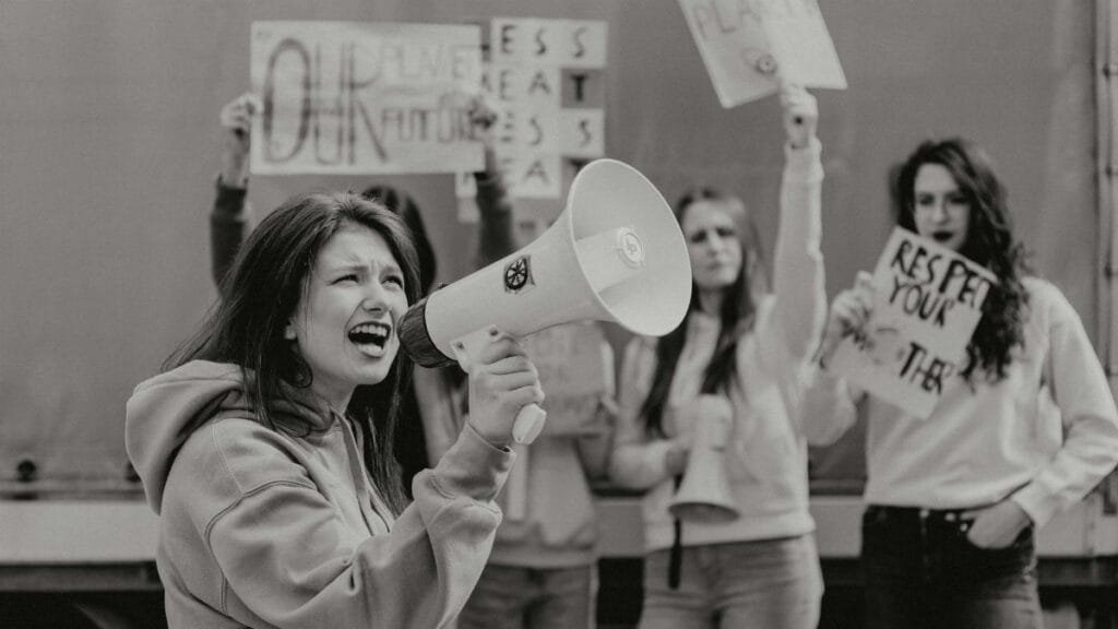Group of activists protesting with signs and a megaphone for environmental causes.