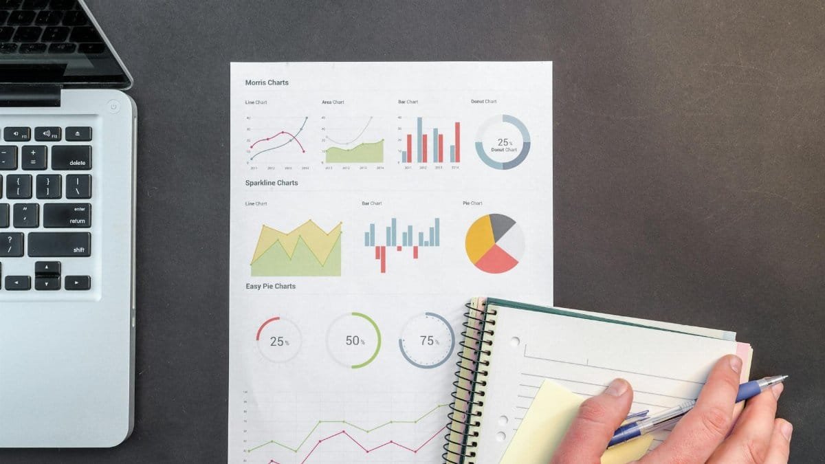 Overhead view of a business desk with charts and a laptop, ideal for data analysis concepts.