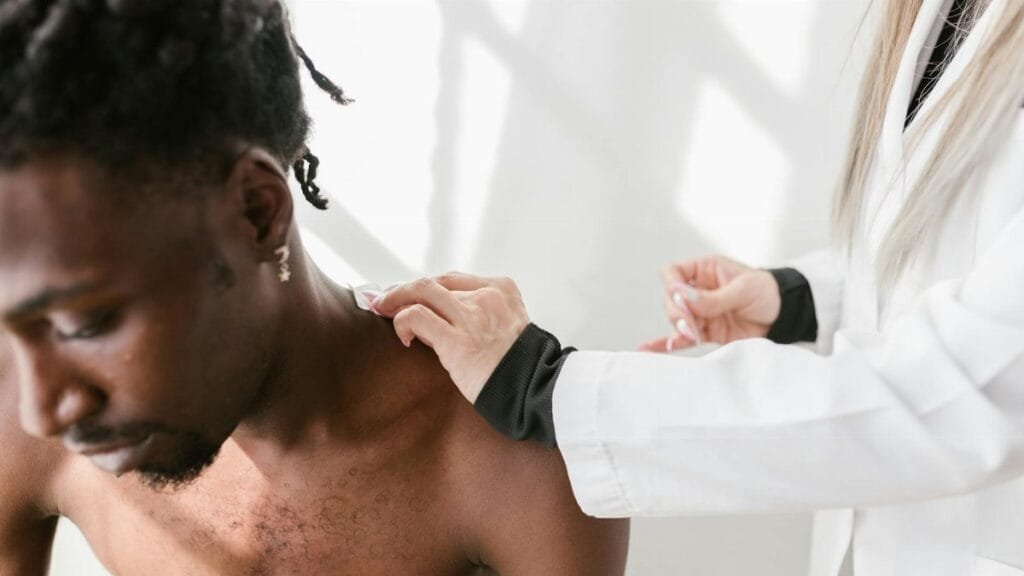 Close-up of a man receiving a shoulder massage for pain relief indoors.