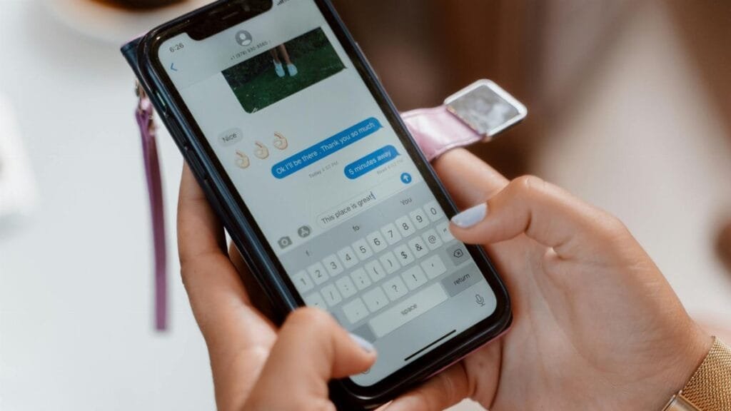 Woman typing on a smartphone, sending a text message with emoji.