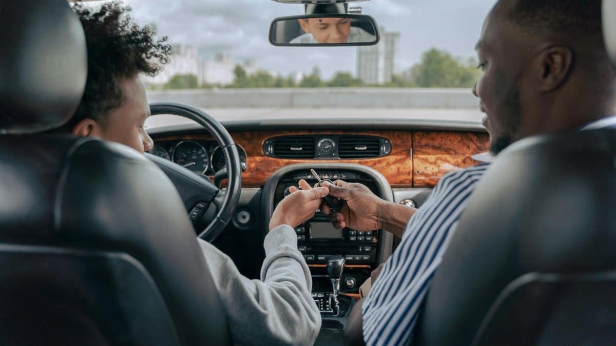 Father and teenage son inside car learning to drive, fostering bonding and guidance.