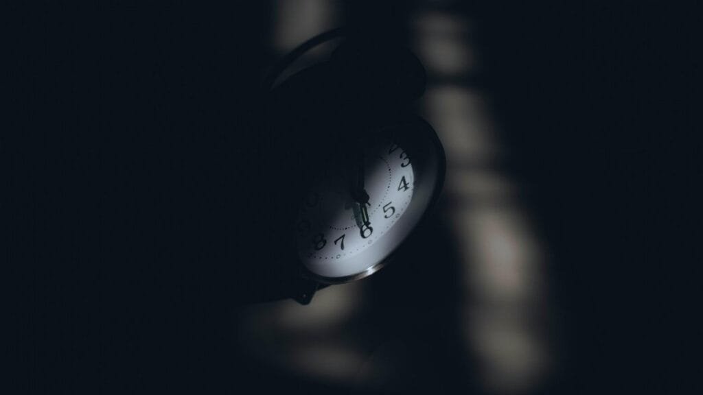 A dimly lit analog clock casting shadows, evoking a sense of mystery and time passage.