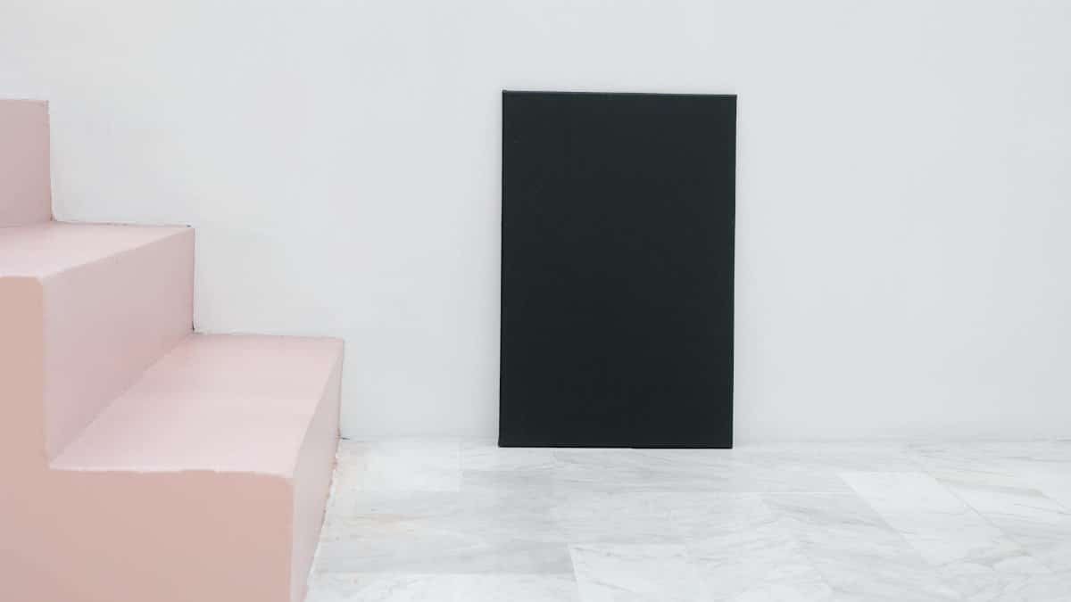 A minimalist interior scene featuring pink steps, a black canvas, and a white background.