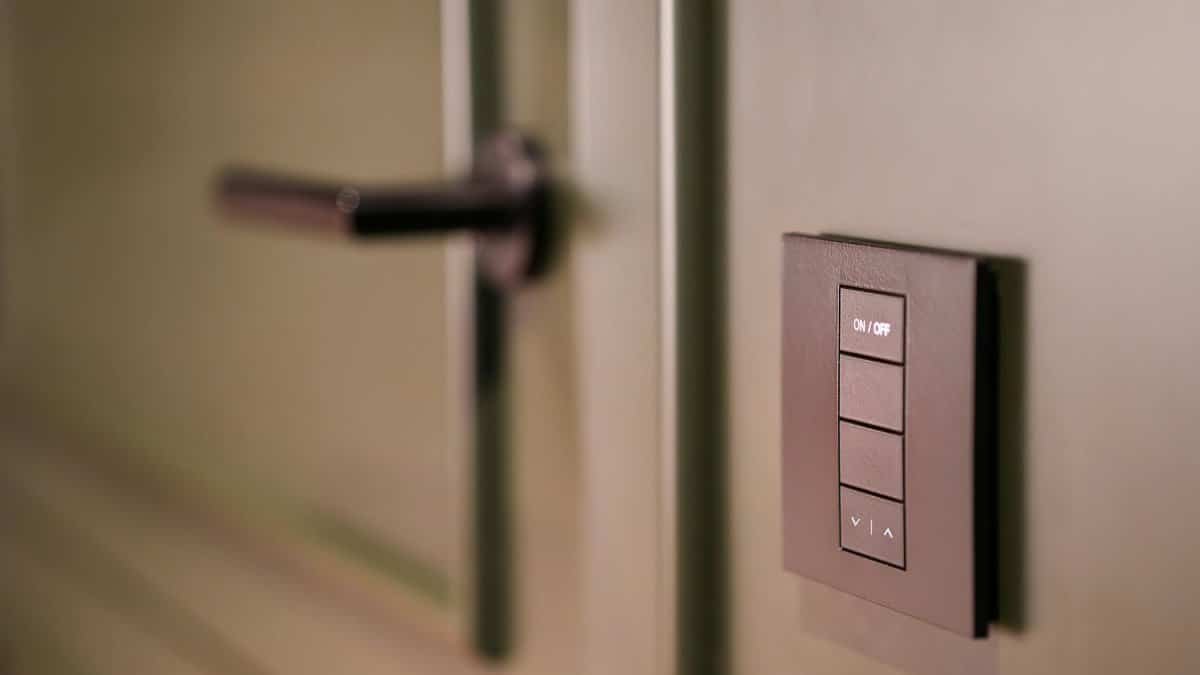 A smart light switch on a wall next to a modern door handle, emphasizing home automation.