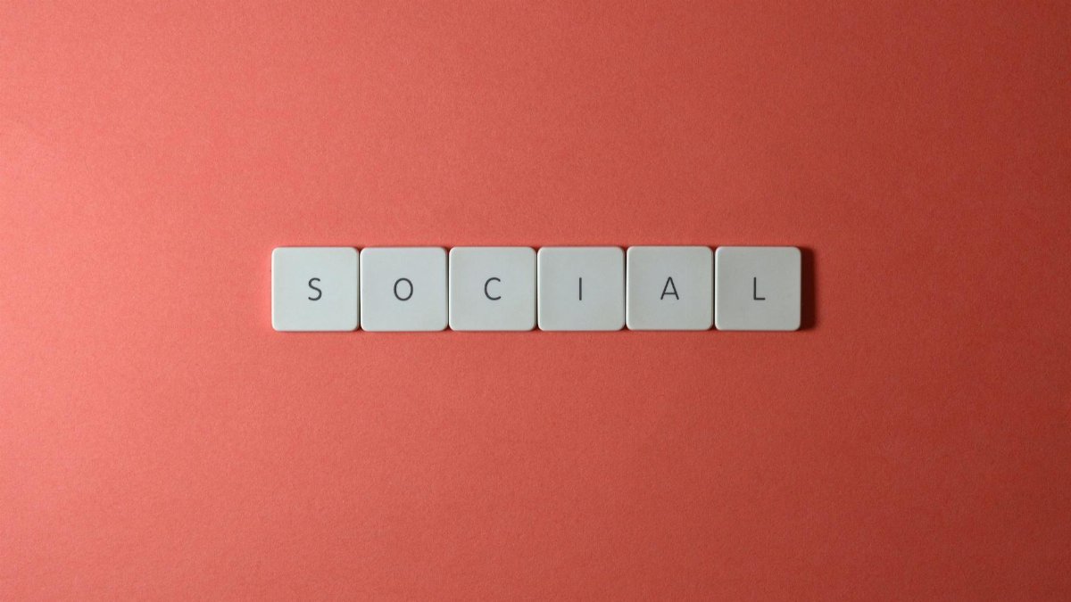 Close-up of the word 'SOCIAL' formed with tiles on a red surface, offering copyspace.
