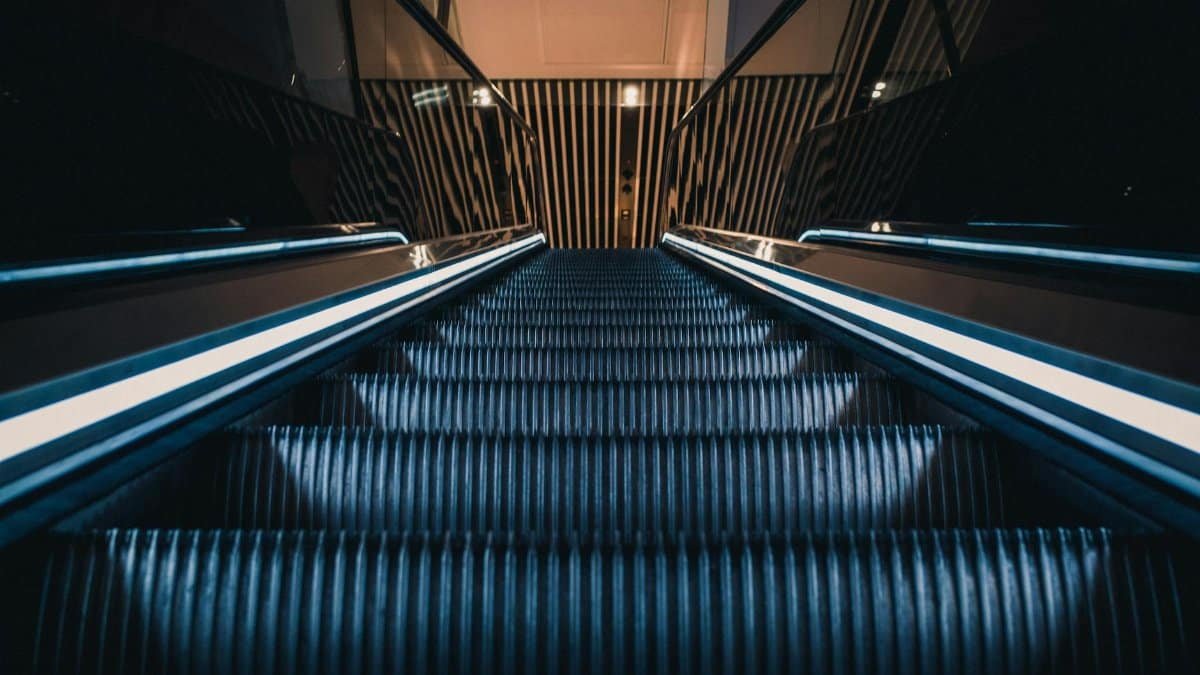 A sleek modern escalator with glowing sides, captured in a unique upward perspective.