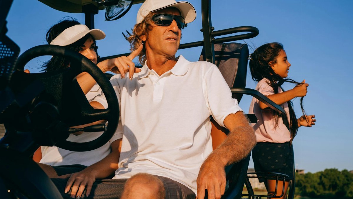 A family enjoying leisure time together in a golf cart on a sunny day.