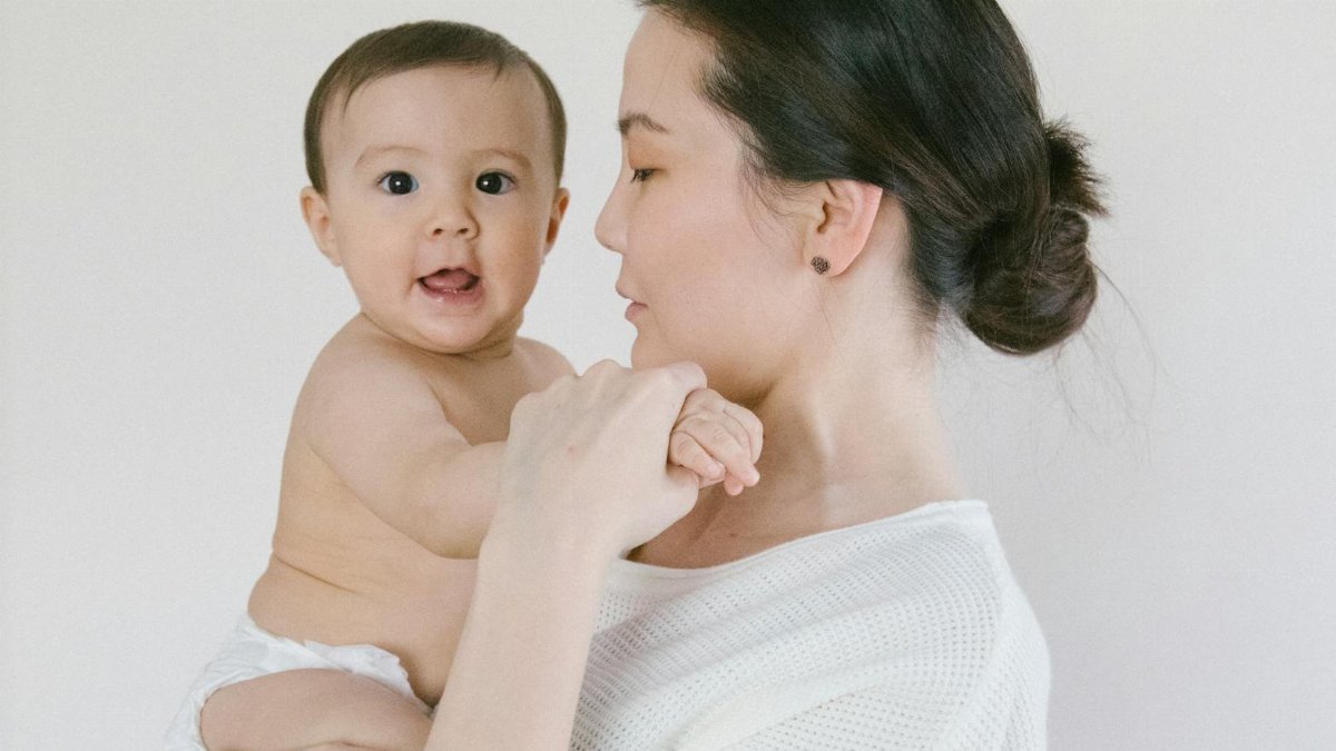 A heartwarming moment of a mother holding her baby indoors, conveying love and care.