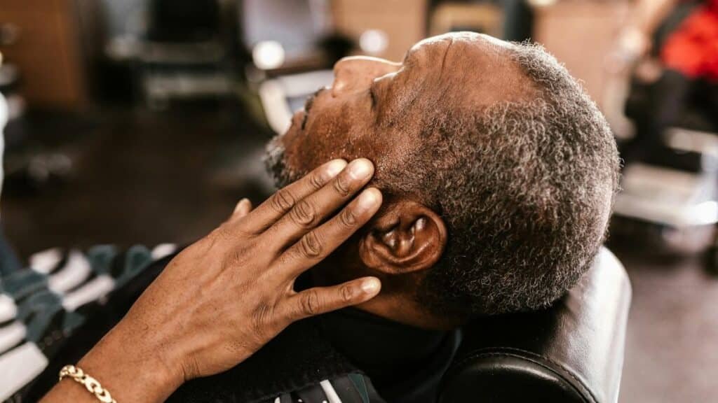A mature man enjoys a relaxing moment at a barbershop, showcasing calm and comfort.