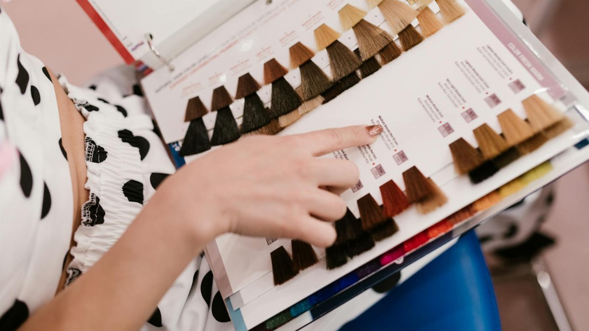 Woman selecting hair color samples in a salon, showcasing shades of brown and blonde.