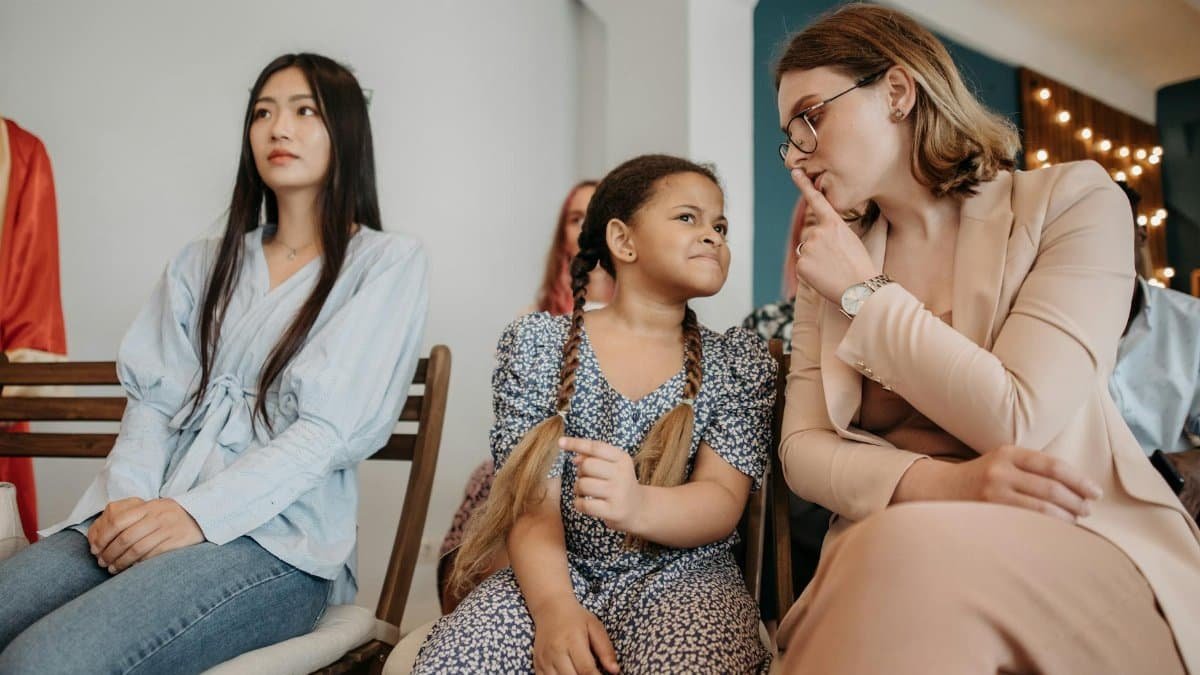 A woman shushes a child in a social gathering, promoting silence.