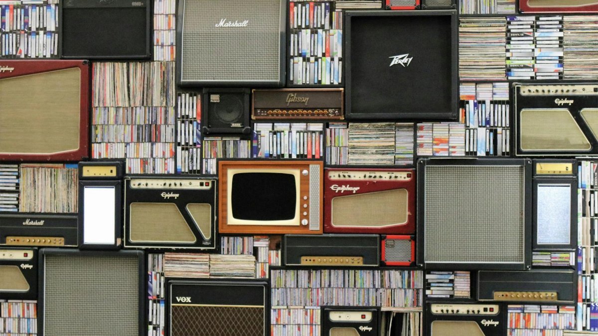 A wall of vintage speakers and TVs surrounded by books and records in a creative display.