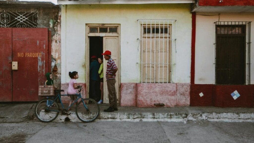 Urban street view with people near a vintage house and a bicycle.
