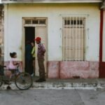 Urban street view with people near a vintage house and a bicycle.