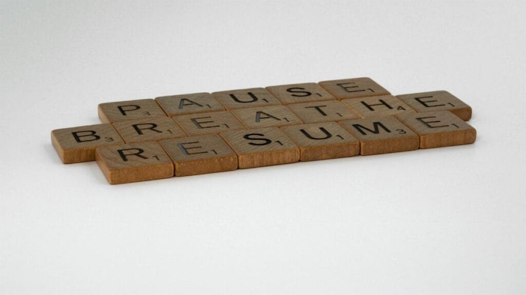 Scrabble tiles spelling 'Pause, Breathe, Resume' on a white background, symbolizing mindfulness and relaxation.