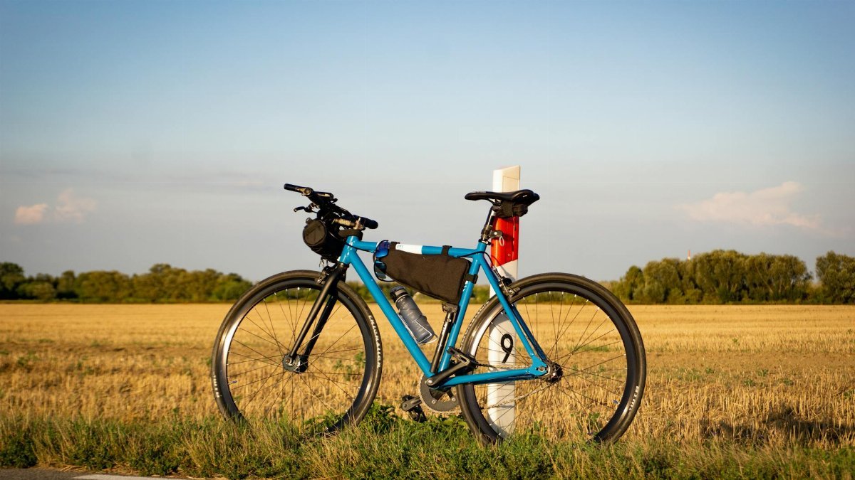 A bicycle leaning against a marker post in the countryside near Warsaw, Poland, during golden hour.