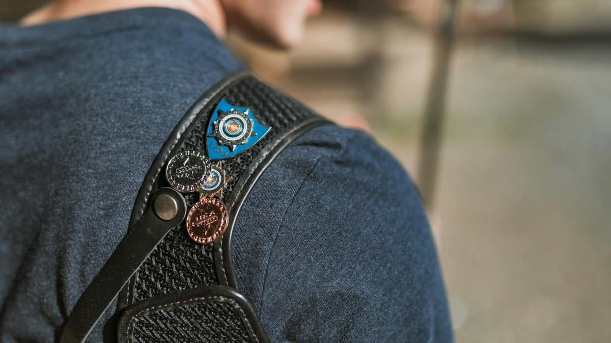 Close-up view of a person wearing medals on a shoulder strap, outdoors.