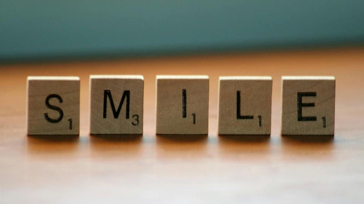 Scrabble tiles spelling 'Smile' on a wooden surface. Creative and uplifting concept.