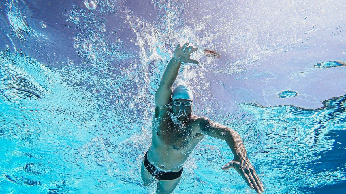 Dynamic shot of a male swimmer in action underwater, showcasing athletic skill and technique.