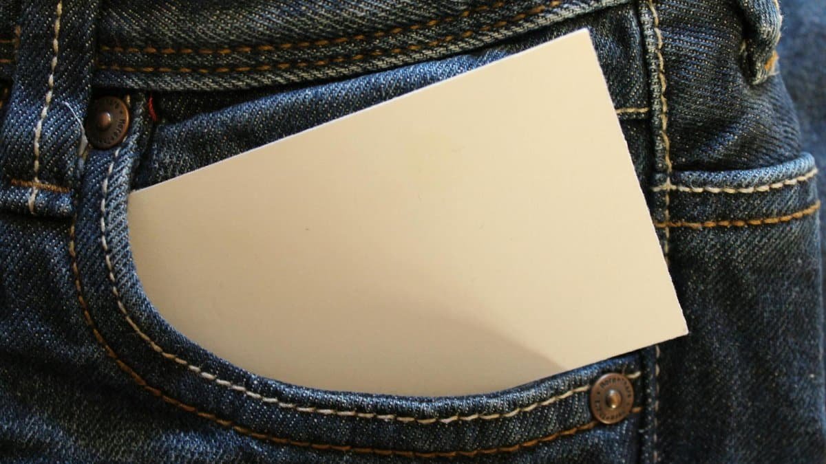 A blank note pad sticking out of the front pocket of a pair of blue denim jeans.