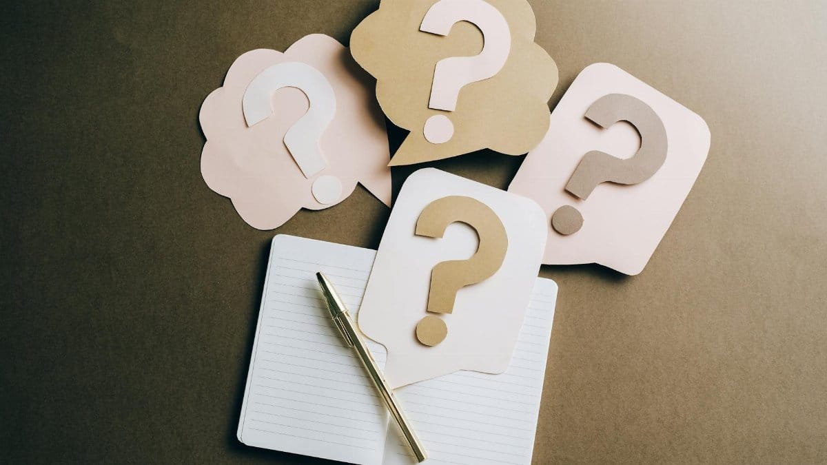 Flat lay of question mark paper crafts on a notebook, symbolizing questions and ideas.