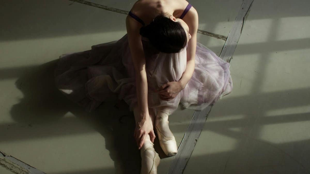 Elegant ballerina in delicate light, resting after a practice session.