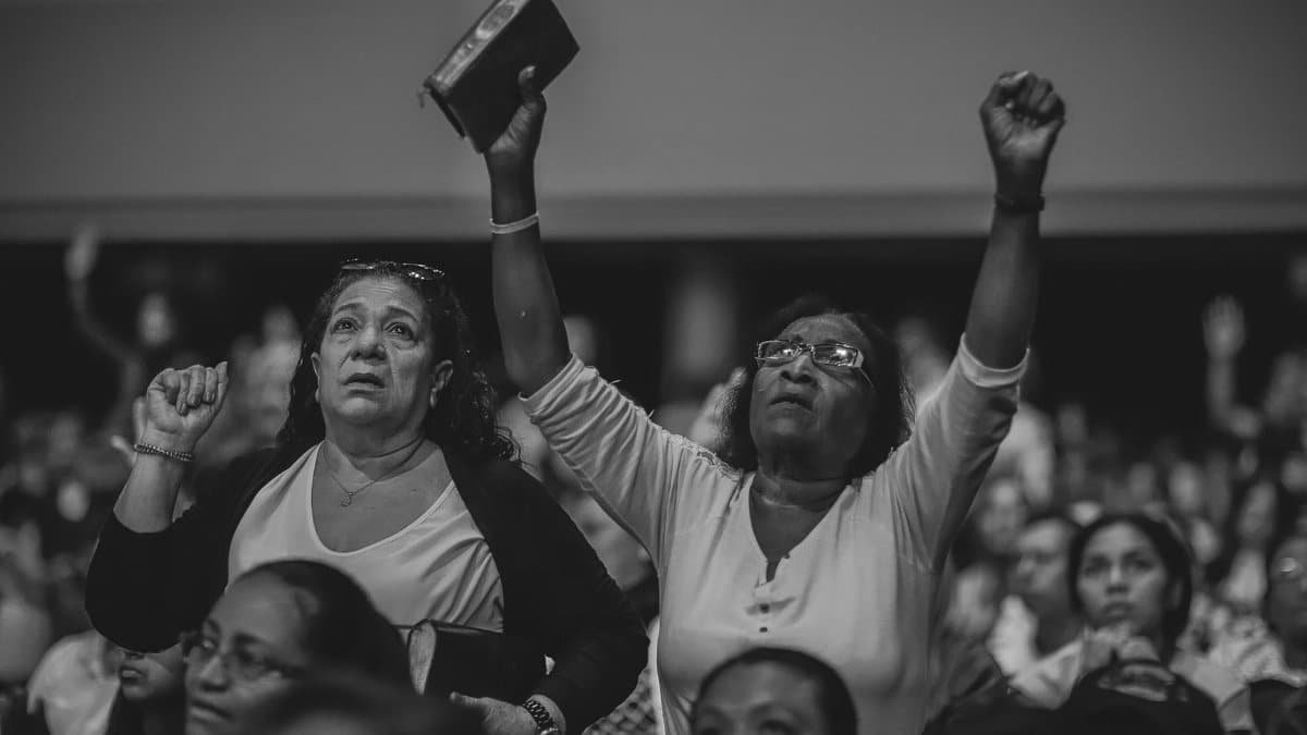 A heartfelt moment of worship in a crowded indoor religious gathering.