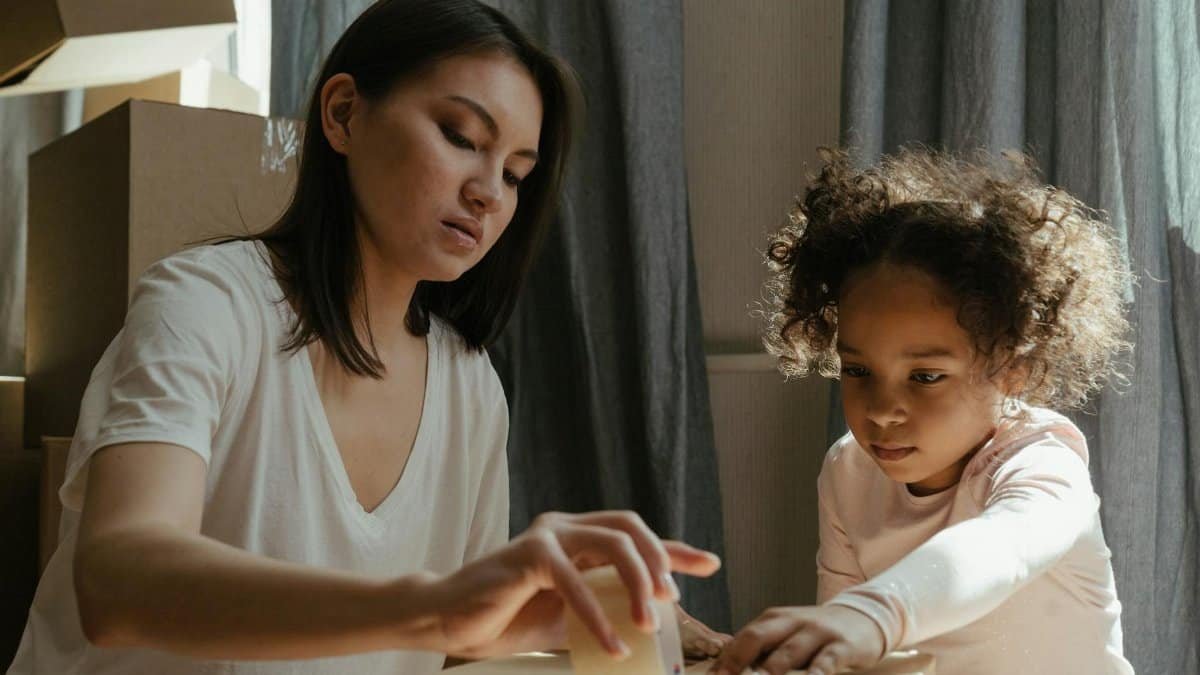 A young mother and her daughter packing moving boxes in their new home.